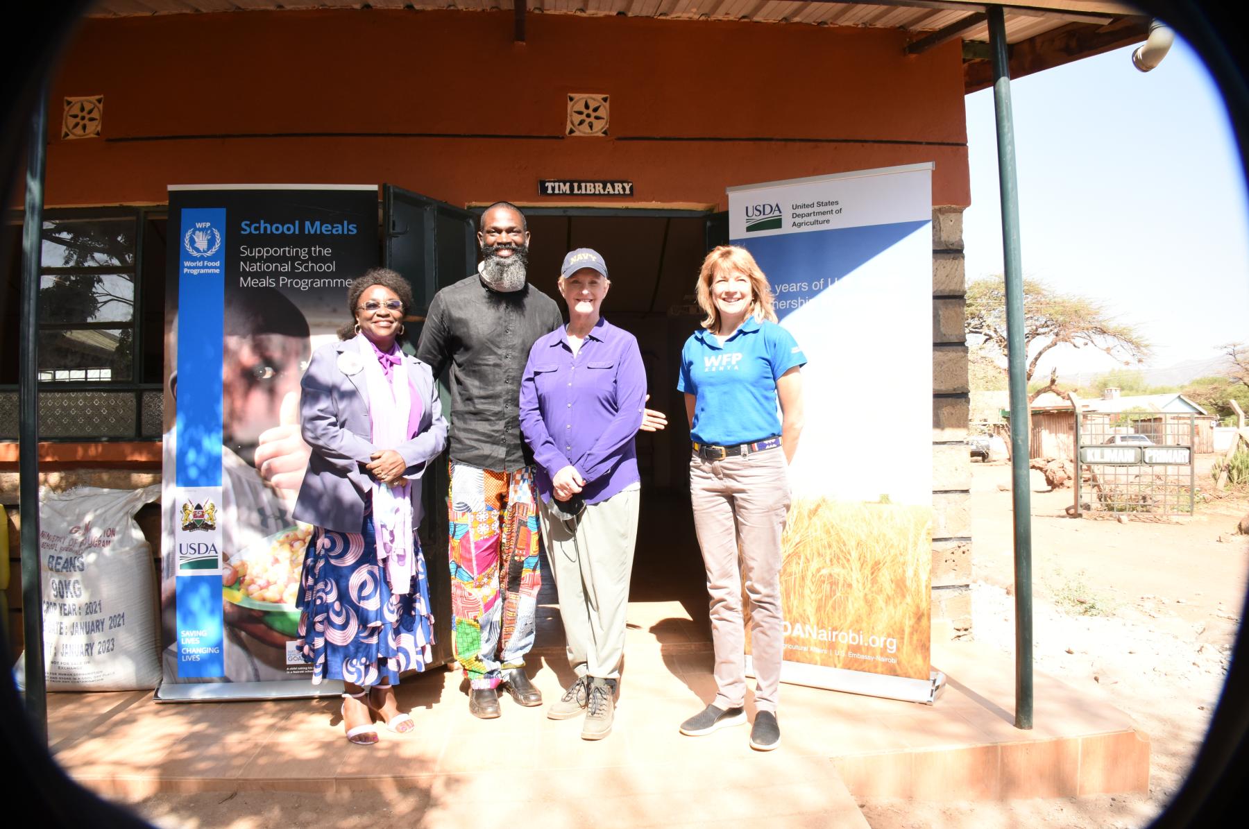 Four individual standing in front of school in Kenya