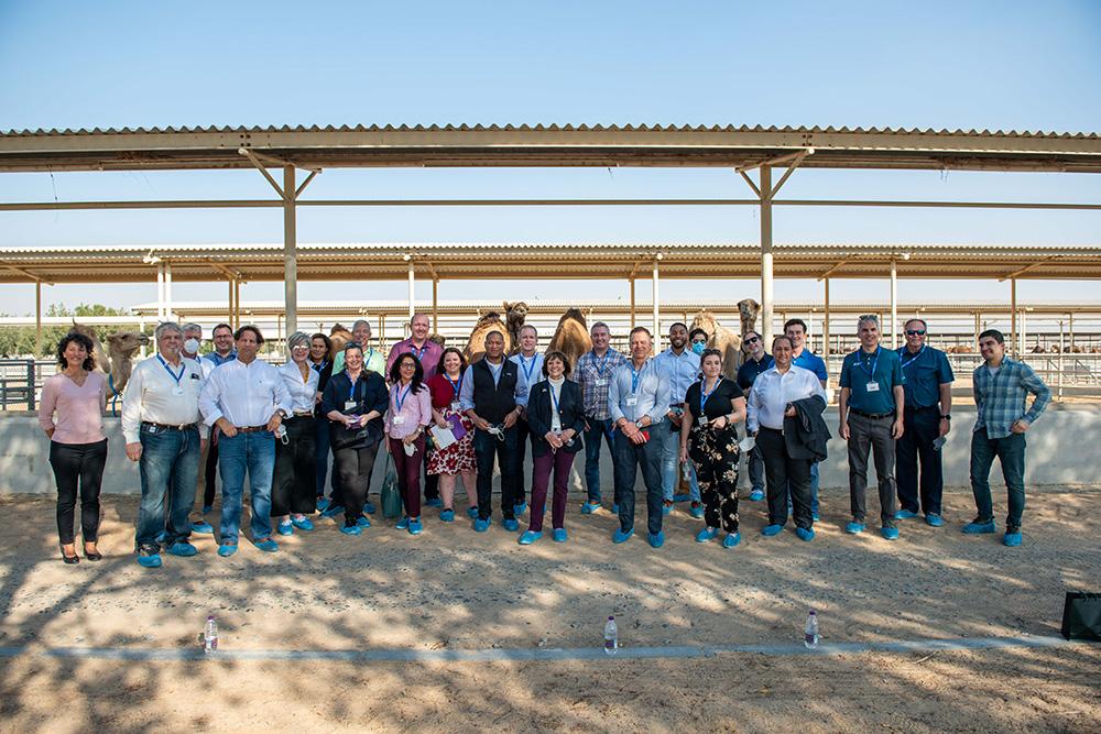 The delegation and the camels pose for a group photo.