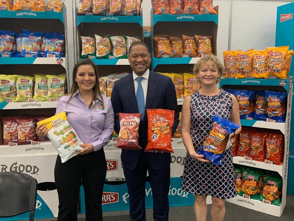 Three individuals holding bags of snack chips