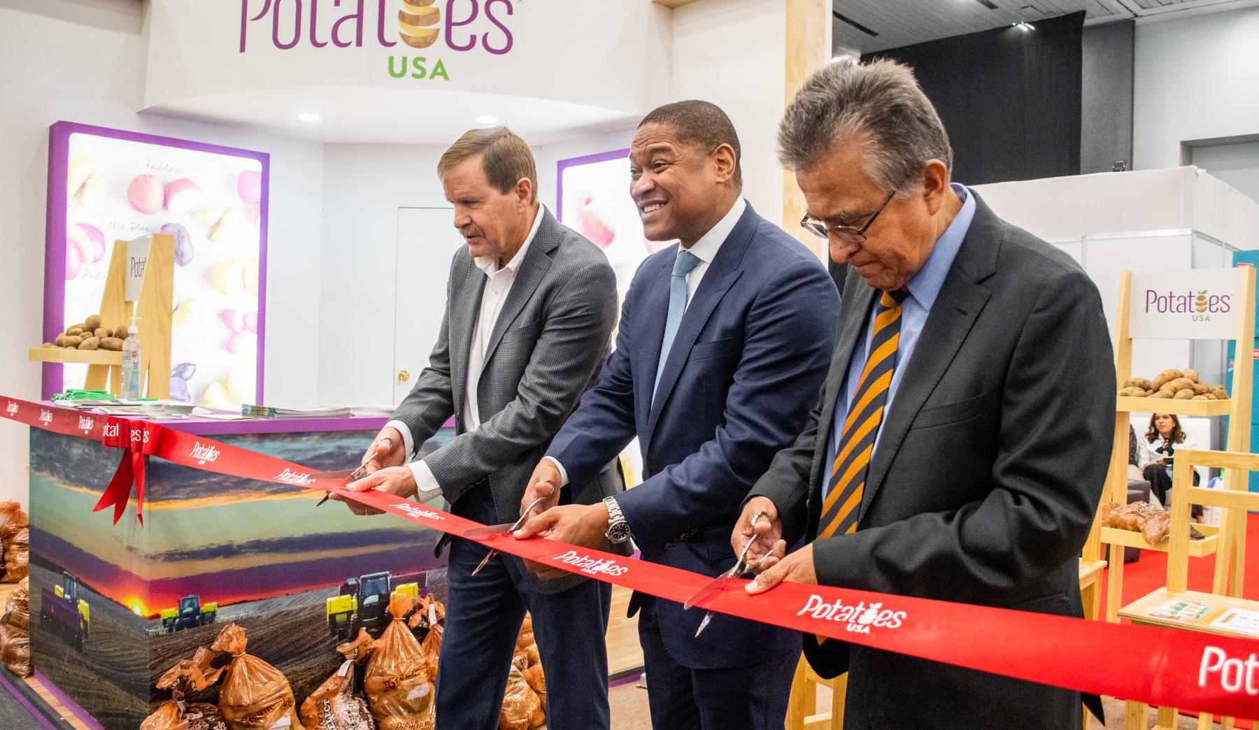 Three men cutting a red ribbon