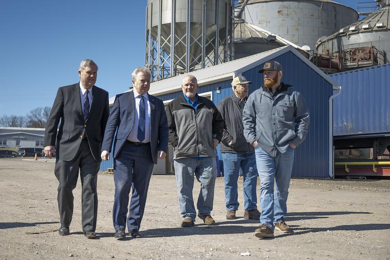 Five men in front of grain silos.