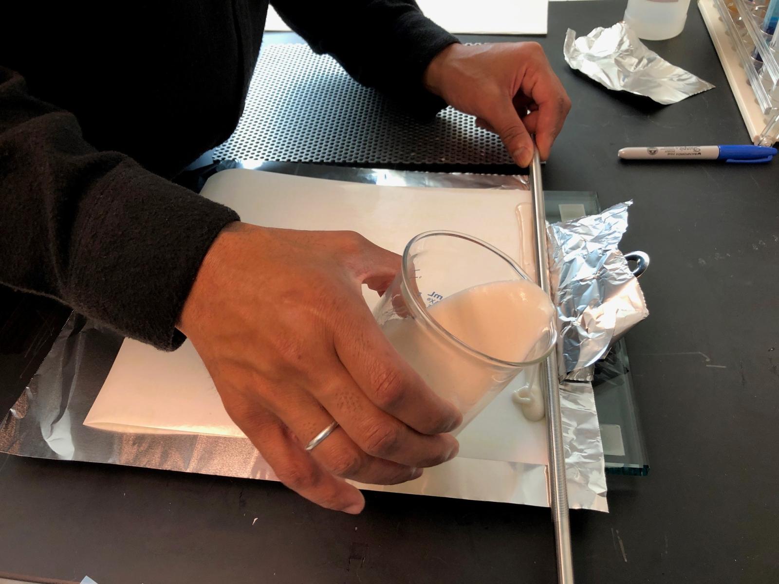 A scientist pours an experimental adhesive compound during the research process. 