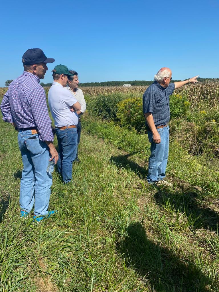 Farmer, Bobby Hutchison standing in a wheat field, surveying his climate-smart, conservation-focused crops and discusses his farming success with members of a delegation from Argentina, Paraguay, and Uruguay.