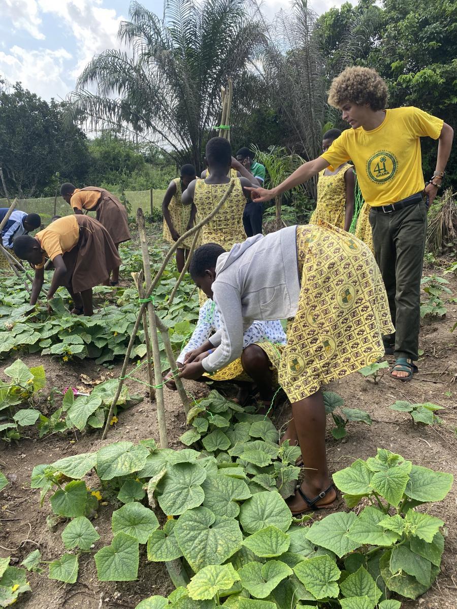 A teacher (right) works with his Ghanaian students in a field on a 4-H project. 