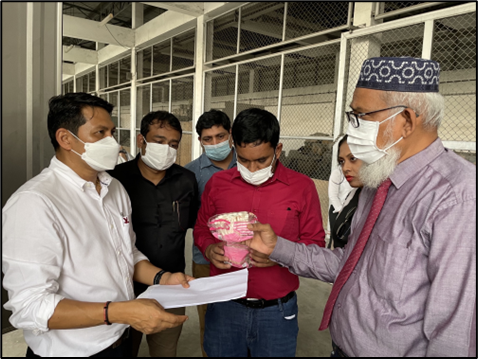 A group of six people huddle together and are discussing something written on a piece of paper. 